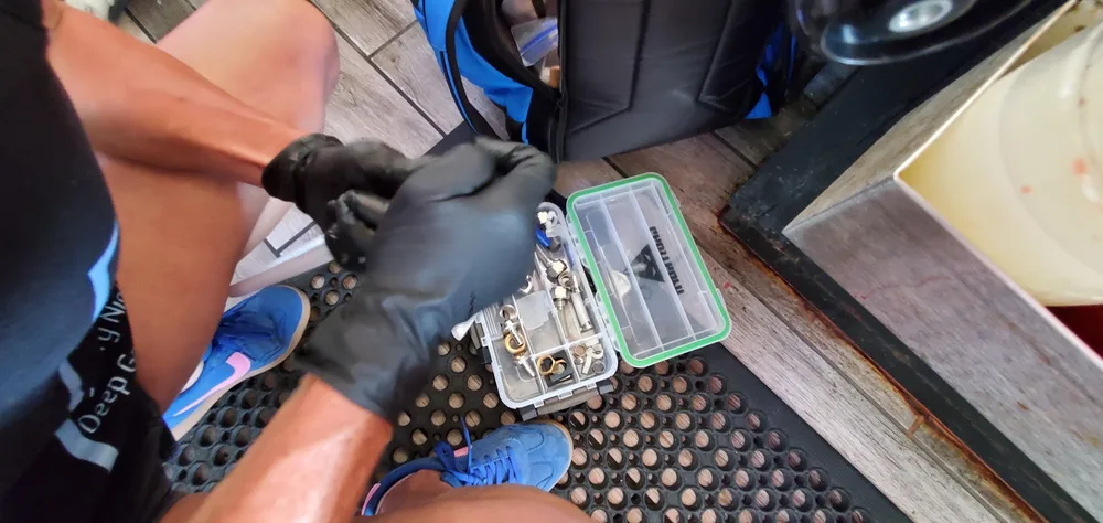 Gloved technician sorting faucet hardware into a parts organizer during a faucet teardown